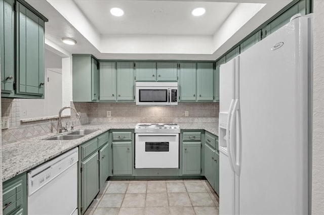 kitchen with sink, light tile patterned floors, green cabinets, white appliances, and decorative backsplash