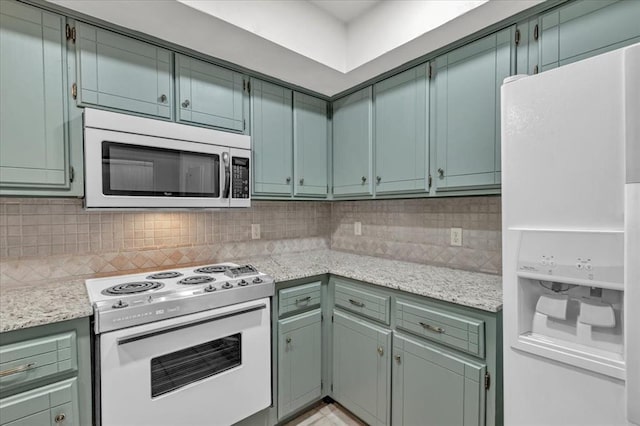 kitchen with light stone counters, backsplash, and white appliances