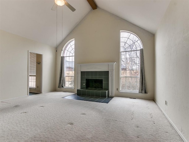 unfurnished living room featuring beam ceiling, ceiling fan, carpet flooring, and a fireplace