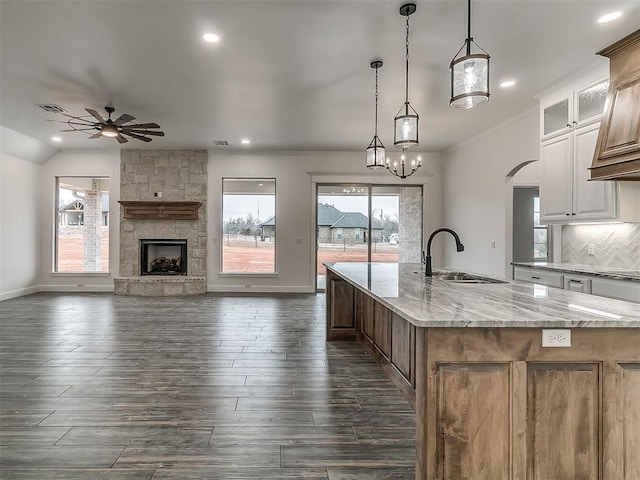 kitchen with pendant lighting, sink, white cabinets, a large island with sink, and light stone countertops