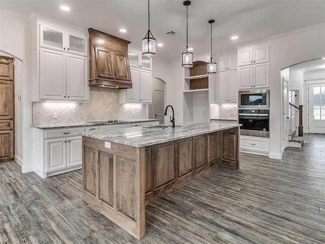 kitchen with white cabinetry, appliances with stainless steel finishes, sink, and an island with sink