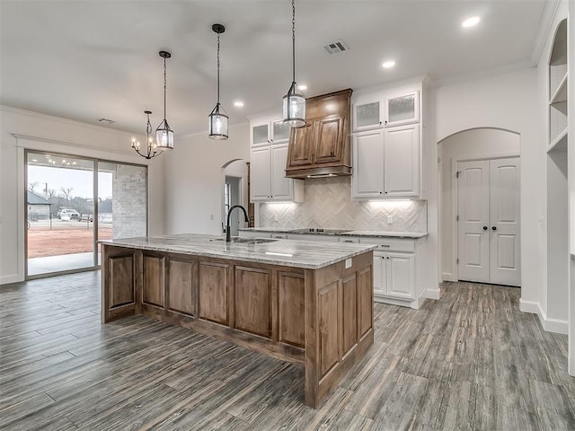 kitchen featuring tasteful backsplash, sink, white cabinets, light stone counters, and a spacious island