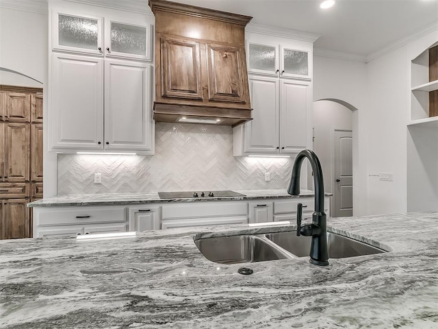 kitchen with white cabinetry, sink, custom exhaust hood, ornamental molding, and black electric stovetop