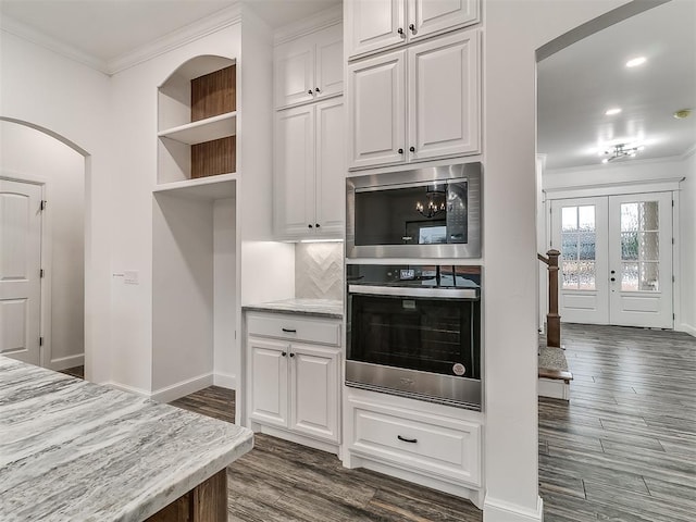 kitchen featuring dark hardwood / wood-style floors, stainless steel microwave, white cabinets, light stone counters, and crown molding