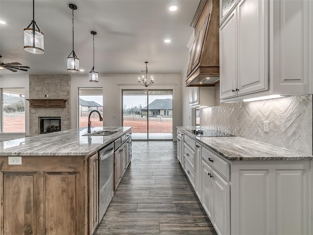 kitchen with a large island, sink, white cabinetry, decorative light fixtures, and custom exhaust hood