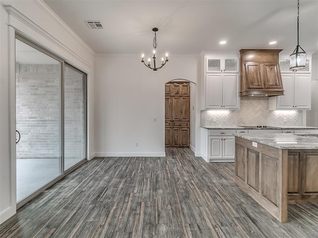 kitchen with white cabinets, decorative backsplash, light stone counters, crown molding, and dark wood-type flooring