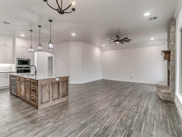 kitchen featuring ceiling fan with notable chandelier, white cabinets, hanging light fixtures, stainless steel appliances, and a spacious island