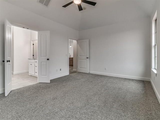 unfurnished bedroom with connected bathroom, vaulted ceiling, light colored carpet, and ceiling fan