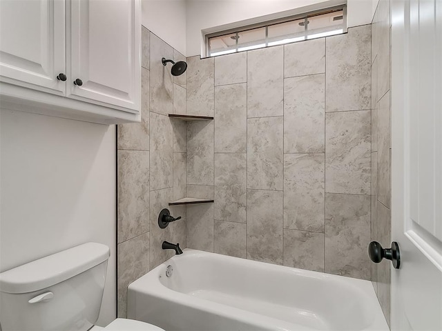 bathroom featuring tiled shower / bath combo and toilet