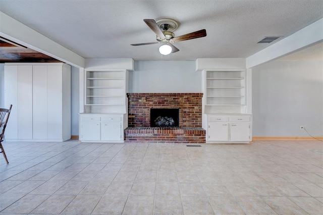 unfurnished living room featuring a brick fireplace, built in features, a textured ceiling, and ceiling fan