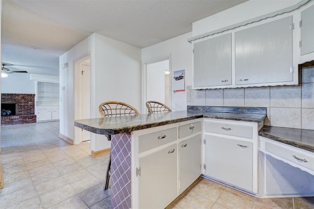 kitchen featuring white cabinetry, a breakfast bar area, kitchen peninsula, and ceiling fan