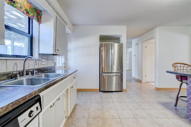 kitchen with sink, stainless steel fridge, dishwasher, white cabinetry, and decorative backsplash