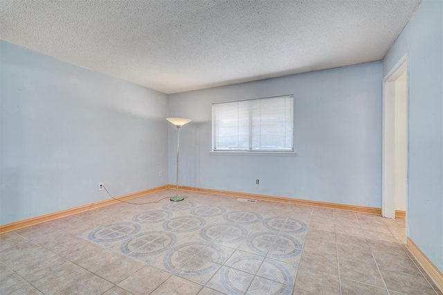 tiled empty room with a textured ceiling