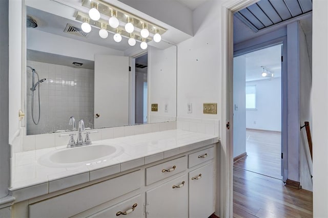 bathroom with vanity, wood-type flooring, and tiled shower