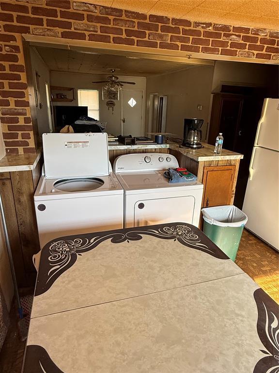 clothes washing area featuring ceiling fan and brick wall