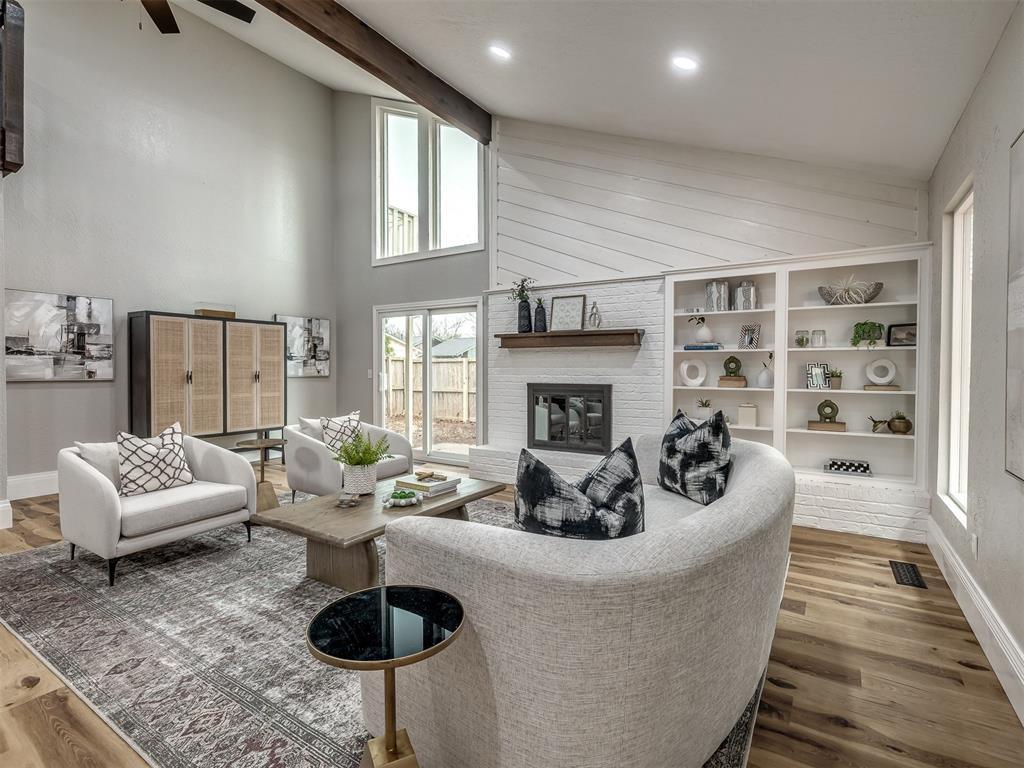 living room featuring hardwood / wood-style flooring, a brick fireplace, and beam ceiling