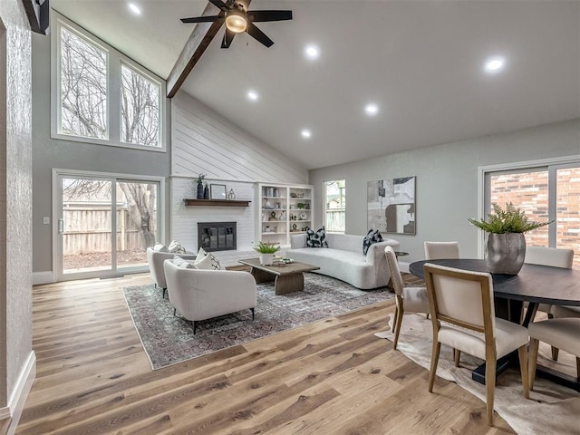 living room featuring plenty of natural light, a fireplace, high vaulted ceiling, and light wood-type flooring