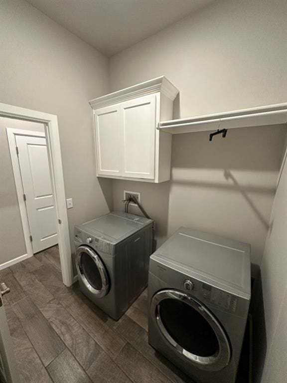 washroom with dark wood-type flooring, cabinets, and separate washer and dryer