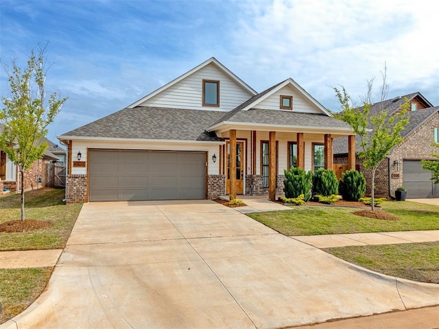 view of front of house with a garage, covered porch, and a front lawn