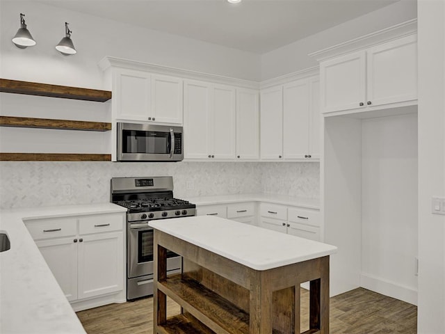 kitchen with hardwood / wood-style flooring, white cabinetry, hanging light fixtures, stainless steel appliances, and tasteful backsplash