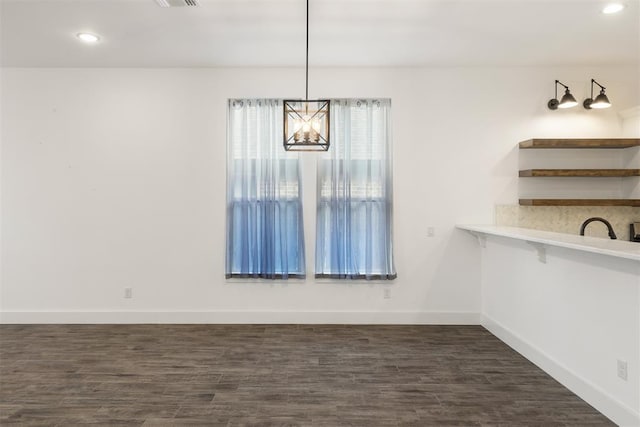 unfurnished dining area with dark hardwood / wood-style flooring and a chandelier