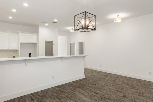 kitchen with a kitchen bar, white cabinetry, tasteful backsplash, decorative light fixtures, and dark hardwood / wood-style flooring