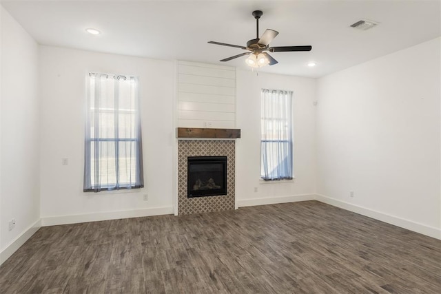 unfurnished living room featuring ceiling fan, a fireplace, and dark hardwood / wood-style floors