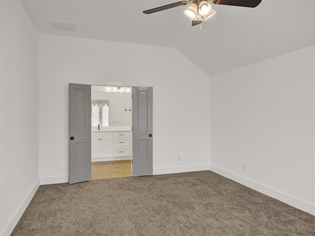 unfurnished bedroom featuring ceiling fan, lofted ceiling, light colored carpet, and ensuite bath