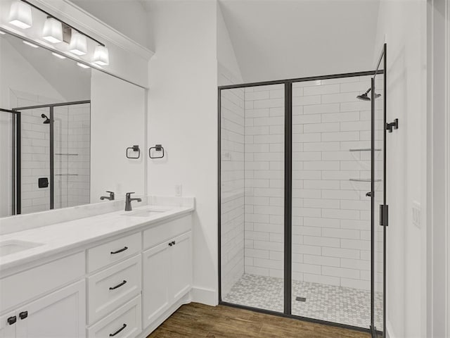 bathroom featuring vanity, vaulted ceiling, hardwood / wood-style floors, and a shower with shower door