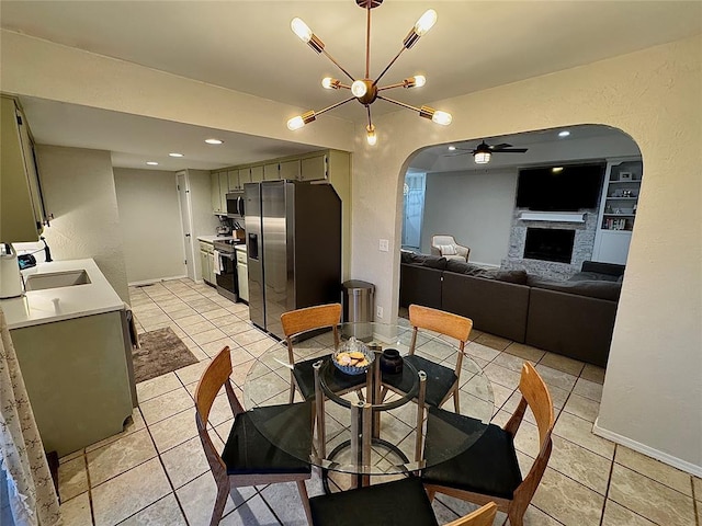 dining space featuring sink, light tile patterned floors, ceiling fan with notable chandelier, and built in shelves