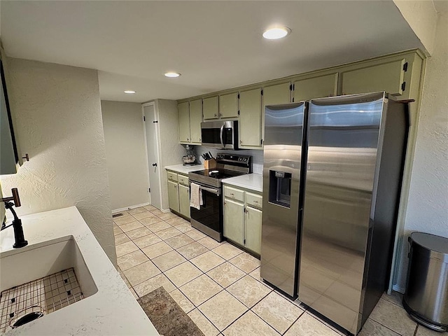 kitchen featuring appliances with stainless steel finishes, sink, green cabinets, and light tile patterned floors