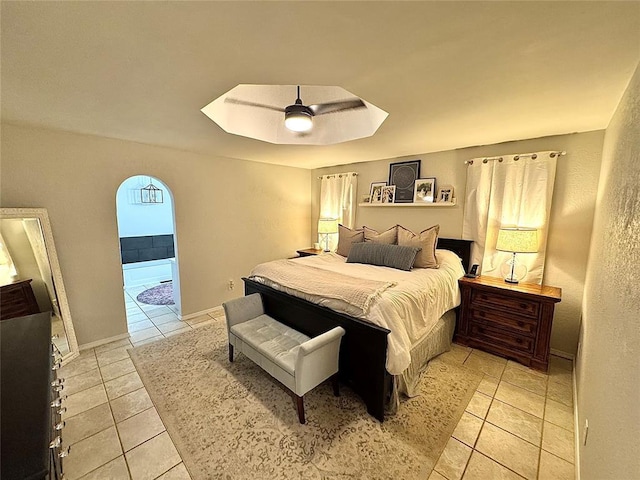 bedroom featuring ceiling fan, a tray ceiling, and light tile patterned floors