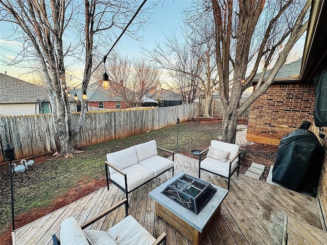 deck at dusk featuring grilling area and an outdoor living space with a fire pit