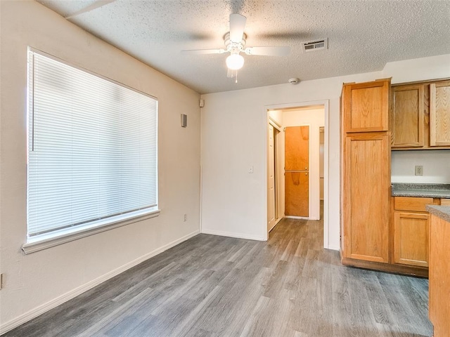 kitchen featuring ceiling fan, light hardwood / wood-style flooring, and a textured ceiling