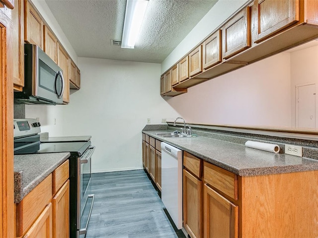 kitchen with dark hardwood / wood-style flooring, sink, a textured ceiling, and appliances with stainless steel finishes