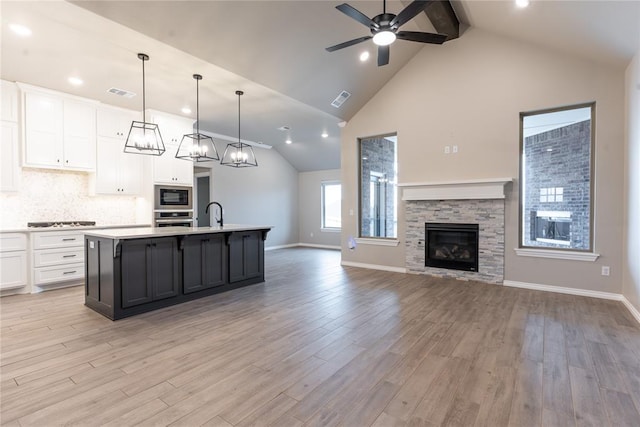 kitchen featuring pendant lighting, white cabinetry, an island with sink, light hardwood / wood-style floors, and black appliances