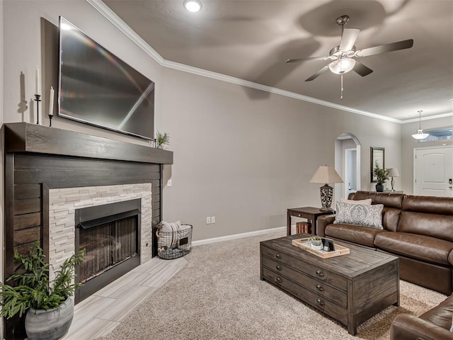 living room featuring crown molding, ceiling fan, a fireplace, and light colored carpet