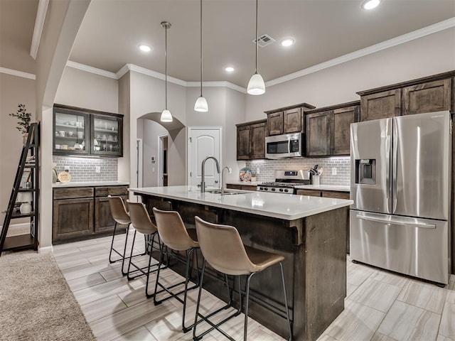 kitchen featuring sink, a kitchen island with sink, hanging light fixtures, dark brown cabinets, and stainless steel appliances