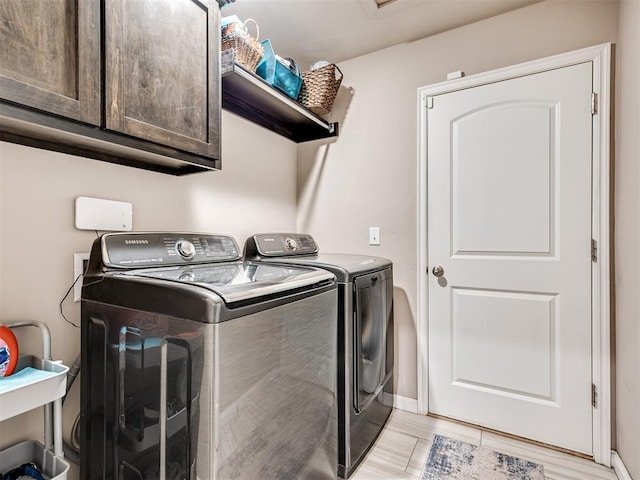 laundry room featuring cabinets, washer and clothes dryer, and light hardwood / wood-style floors