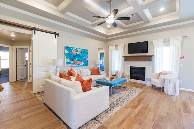 living room with a barn door, coffered ceiling, ceiling fan, and light hardwood / wood-style flooring