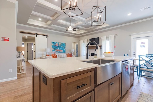 kitchen with sink, dishwasher, a kitchen island with sink, hanging light fixtures, and a barn door