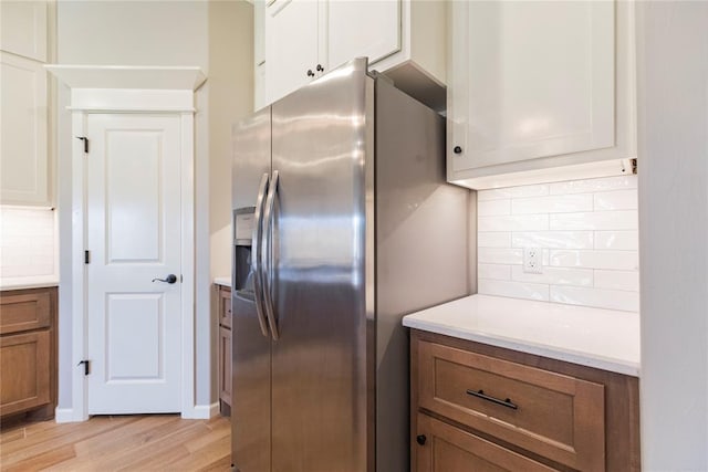 kitchen featuring white cabinetry, stainless steel refrigerator with ice dispenser, backsplash, and light hardwood / wood-style flooring