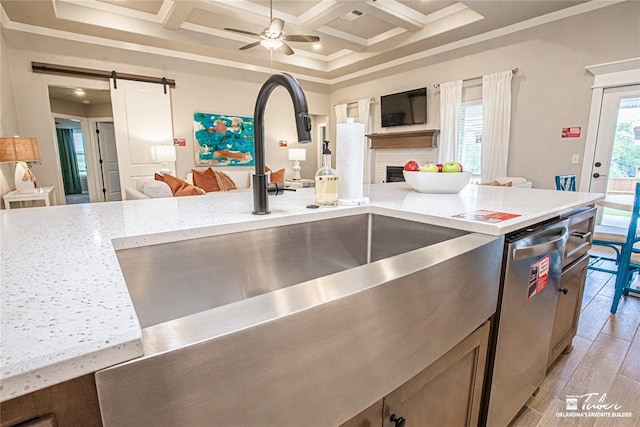 kitchen featuring coffered ceiling, sink, dishwasher, a barn door, and light stone countertops