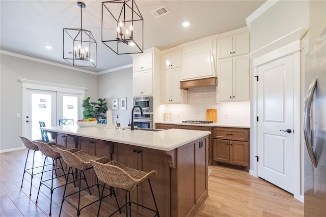 kitchen featuring sink, stainless steel appliances, an island with sink, and white cabinets