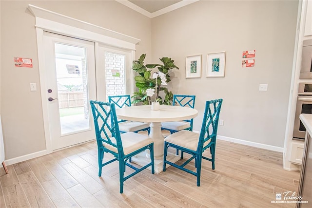 dining room with ornamental molding and light hardwood / wood-style floors