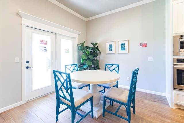 dining space with ornamental molding and light hardwood / wood-style floors