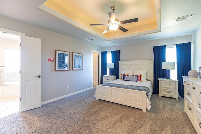 carpeted bedroom featuring a raised ceiling and ceiling fan