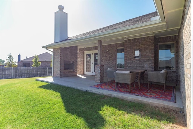 rear view of house with an outdoor brick fireplace, a lawn, and a patio area