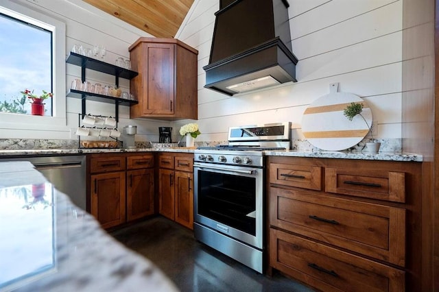 kitchen featuring stainless steel appliances, custom exhaust hood, light stone counters, and wood walls