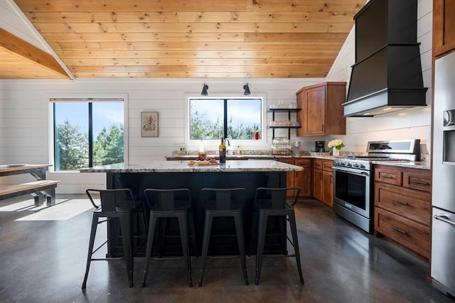 kitchen featuring premium range hood, a kitchen bar, appliances with stainless steel finishes, a kitchen island, and light stone countertops